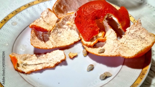Peeled mandarin orange with separated peel and seeds on plate