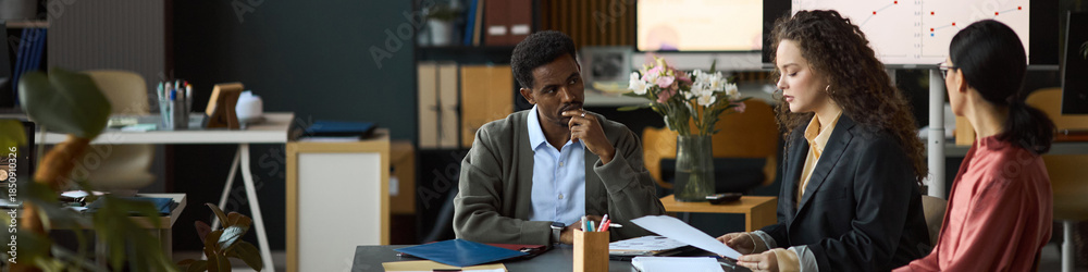 custom made wallpaper toronto digitalMultiethnic group of professionals discussing business documents at office table, Black man listening attentively while Caucasian woman explaining project details to another woman, header