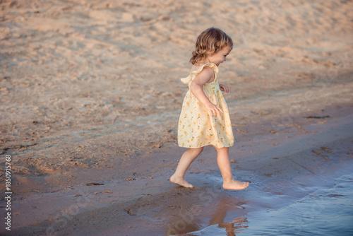 A 3-year-old girl runs along the seashore while walking in summer