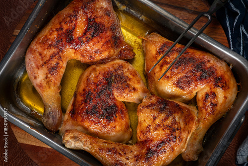 Baked chicken legs in metal baking dish.