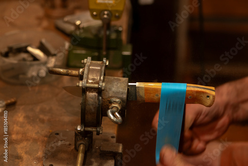 A close-up of a craftsman's hands as he creates a hunting knife.