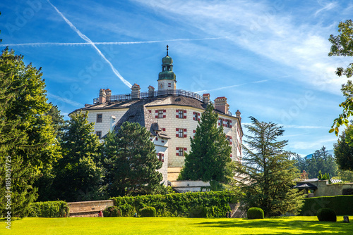 Historic Ambras Castle Under a Bright Blue Sky with Lush Green Gardens