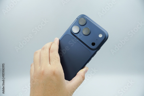 Hands holding an expensive smartphone in the deep blue variant and showing the back of the smartphone with a white background