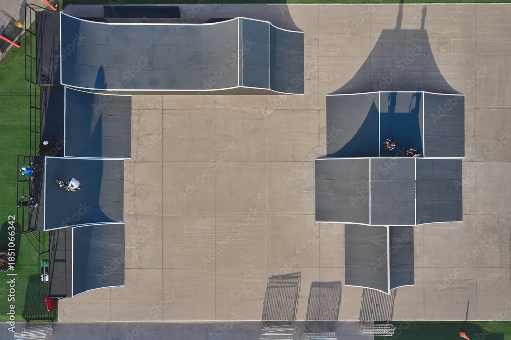 Fototapeta premium Skatepark featuring ramps and obstacles with bmx riders, captured by drone aerial view
