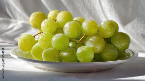 A bright and fresh arrangement of white-backed grapes placed on a white plate, with soft light illuminating their translucent skin and highlighting their beauty