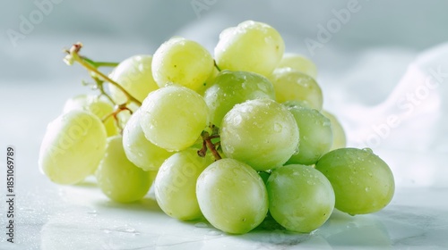 A bright and fresh shot of white-backed grapes, arranged carefully on a white surface, their light green color and smooth texture shining under soft lighting