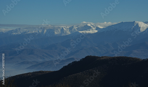 view of big snowed mountain peaks in winter and lower hills at bottom in sunny morning