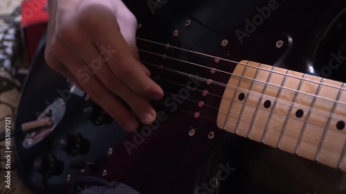 Hands of male musician playing at electric guitar. Mens arms plays solo of rock music. Close up fingers of guitarist at the strings. Beautiful black background at studio. Slow motion Close up