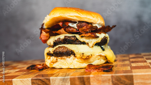 Картината върху платно Delicious double deck bacon cheeseburger on a beautiful wooden board