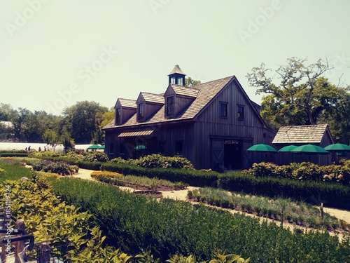 Photography Idyllic summer garden surrounding an old wooden barn house on a warm summer day