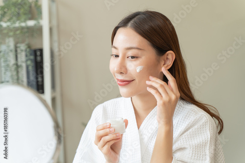 Effortless Elegance: A Serene Moment of Self-Care as a Woman Applies Luxurious Moisturizing Cream for Glowing, Nourished Skin and Unveils the Beauty of Skincare Rituals