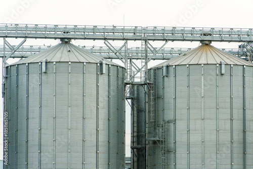 A large modern plant located near a wheat field for the storage and processing of grain crops. view of the granary illuminated by the light of the setting sun against the blue sky. harvest season.
