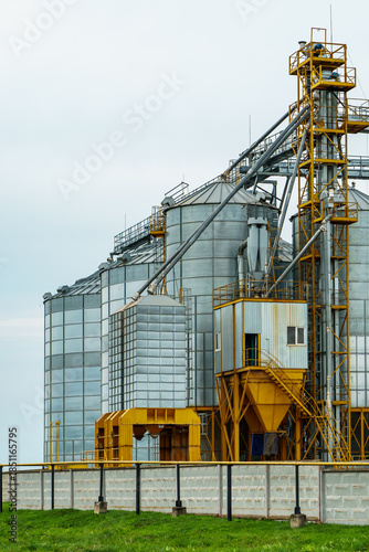 A large modern plant located near a wheat field for the storage and processing of grain crops. view of the granary illuminated by the light of the setting sun against the blue sky. harvest season.