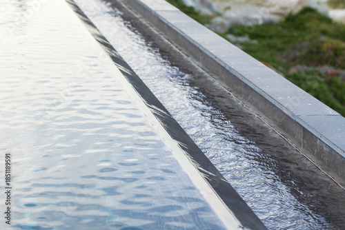 Foto A clean, linear pool edge features a calm, reflective water surface