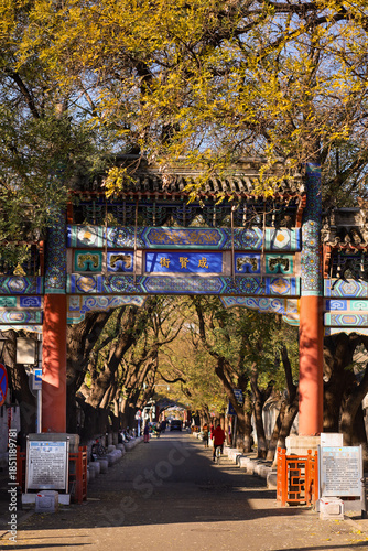 Lama Temple. Colorful Ornate Chinese Arched Gate With Traditional Design And People At The Bottom Of The Temple Entrance