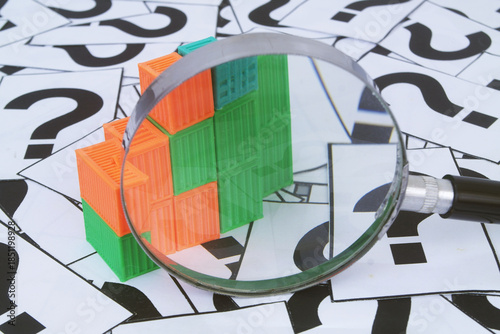 Many containers under magnifying glass on question marks background. Shipping, delivery and ​​transportation questions concept.