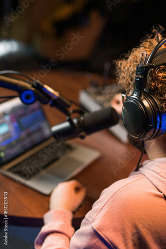 Cheerful young man recording podcast in studio. Confident man with headphones and microphone recording a podcast. Happy guy talking on web radio.