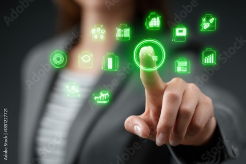 Woman interacts with green business icons using her finger while wearing a gray blazer in a modern office setting