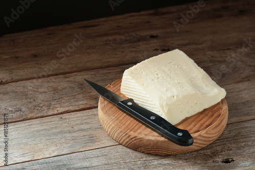 Cheese Block on Wooden Cutting Board With Knife Nearby in a Simple Setting
