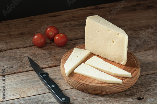 Fresh cheese Served on a Wooden Board With Tomatoes and Knife