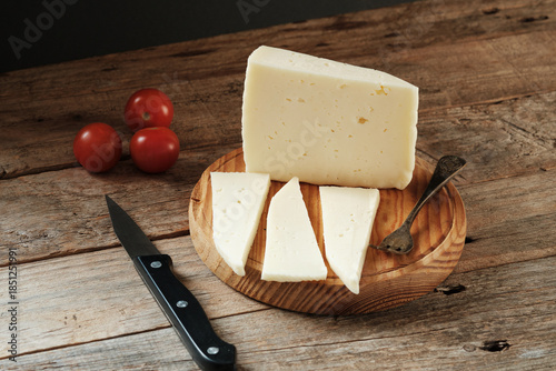 Fresh cheese Served on a Wooden Board With Tomatoes and Knife