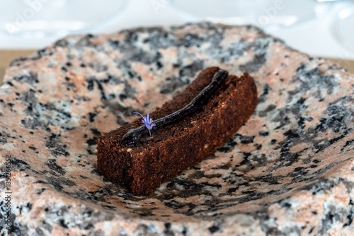 Gourmet chocolate dessert with a floral garnish served on a unique stone plate