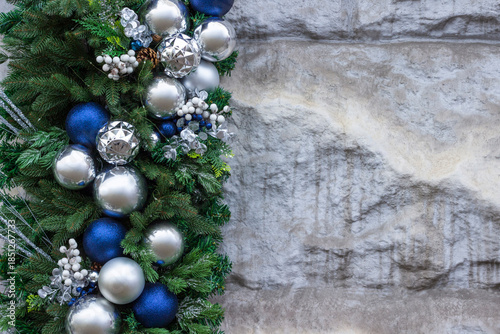 Spruce branches with blue and silver balls on a stone background. Copy space.