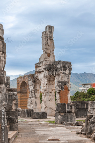 Fotografija Ancient Roman ruins of the Capua Amphitheater with mountain backdrop and modern