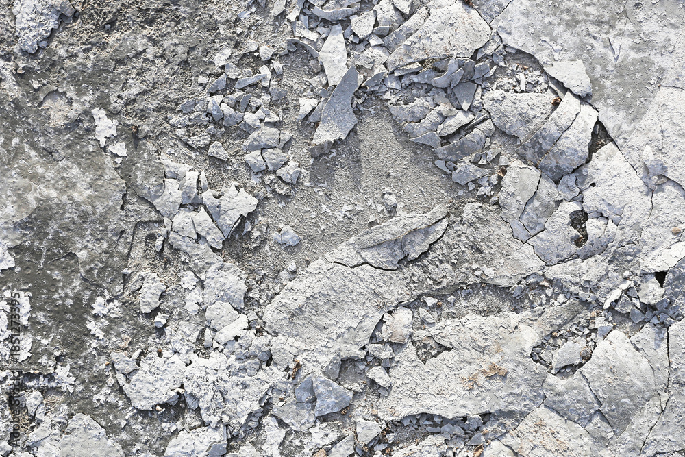 Fototapeta premium Concrete wall texture background. Cracked cement surface closeup. Weathered plaster and stone pattern. Old damaged wall detail. Rough gray construction material. Abstract urban texture. 