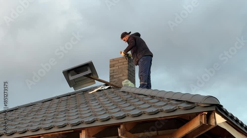 A master stove setter installs a cap on the stove pipe. Heating stove construction.