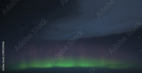 Quadro em tela Low band of green and faint magenta aurora glowing along a distant horizon benea