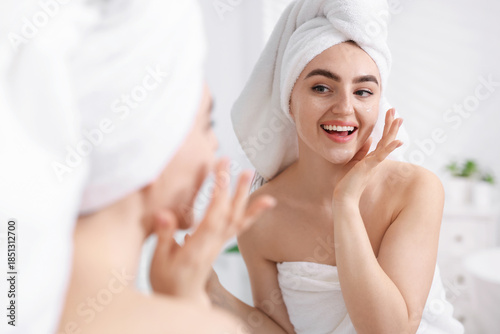 Woman with hair wrapped in towel near mirror indoors