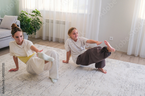 Teenagers practice fitness at home. Girls do sports exercises
