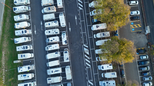 Large outdoor RV parking lot in Cremona, Italy seen from above, rows of motorhomes and camper vans amid urban autumn surroundings