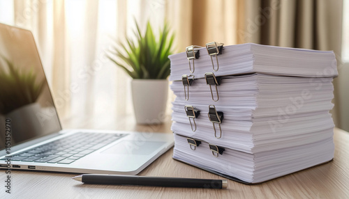 Large stack of documents with binder clips on office desk.