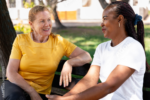 фотографія Diverse senior women friends enjoying outdoor conversation on a park bench, shar