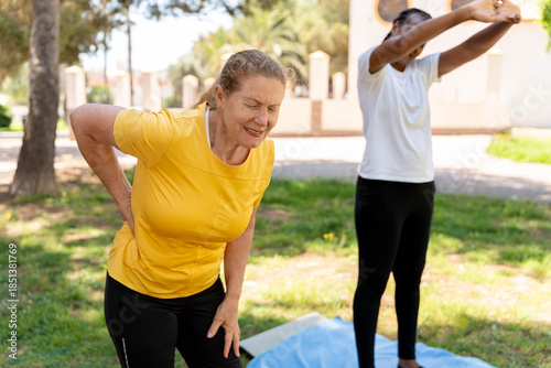 Принти на полотні Senior woman experiencing lower back pain during an outdoor exercise session, ne