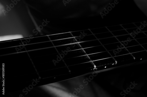 Close-up photo of an acoustic guitar with shadows. Guitar strings, neck, frets and body