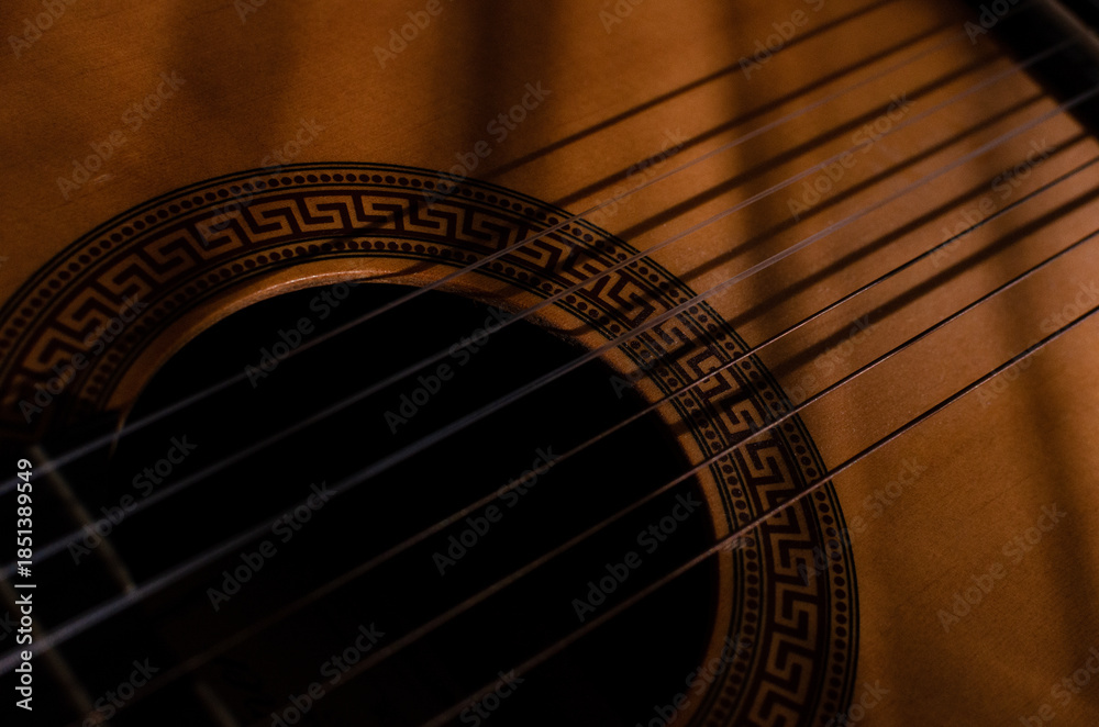 Obraz premium Close-up photo of an acoustic guitar with shadows. Guitar strings, neck, frets and body