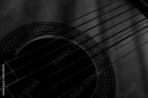 Close-up photo of an acoustic guitar with shadows. Guitar strings, neck, frets and body