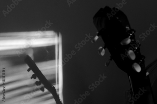 Close-up photo of an acoustic guitar with shadows. Guitar strings, neck, frets and body
