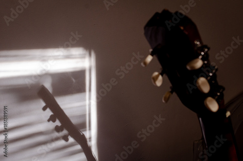 Close-up photo of an acoustic guitar with shadows. Guitar strings, neck, frets and body