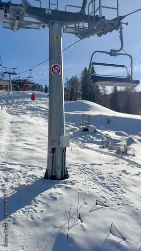 ski chairlift moving over snowy mountain slope on a sunny winter day