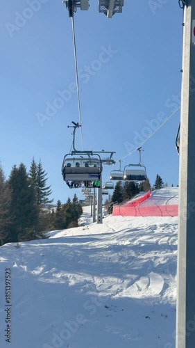 Chairlift ride alongside active ski slope during winter season