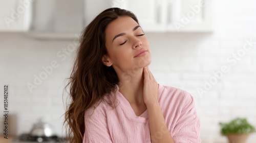 Relaxed woman gently massaging her neck in cozy pink robe Free Download Relaxed woman gently massaging her neck in cozy pink robe - GFXLoad