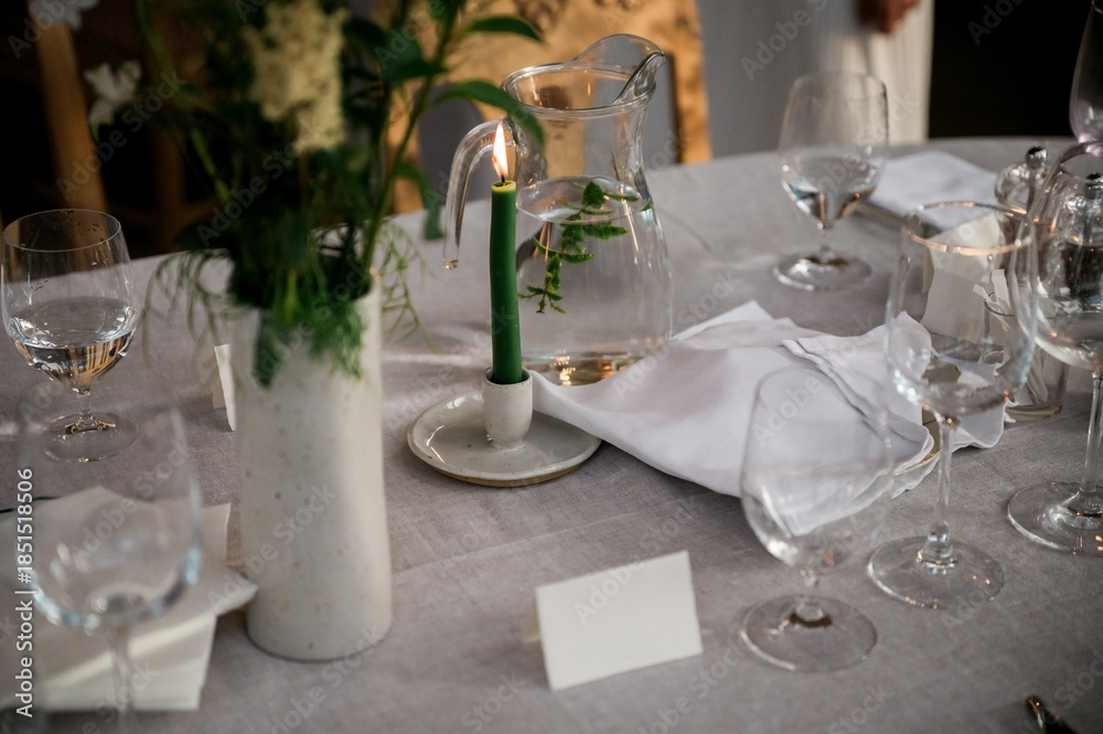 Fototapeta premium Refined table setting with candlelight, crystal glassware, folded linen napkins and fresh greenery, creating an elegant and intimate dining atmosphere for luxury events and celebrations.