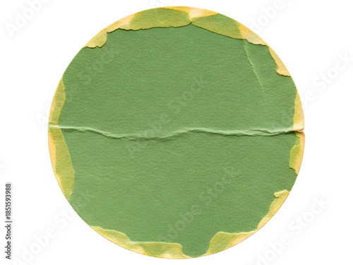 A close-up of a circular, torn green paper sticker with a horizontal crease and frayed yellow edges on a white background.