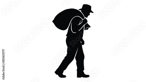 Silhouette of a worker or farmer carrying a heavy sack or bag over their shoulder