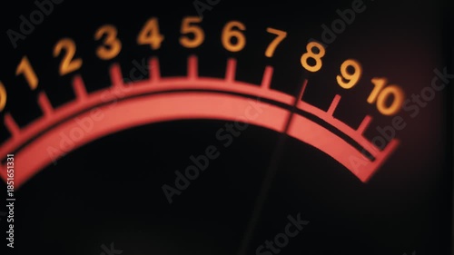 Close-up view of a vintage analog meter needle fluctuating across a red scale. It measures signal strength against a dark background in a professional studio environment.