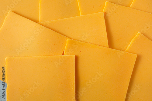 A top down view of several slices of dairy-free cheddar cheese, as a background.